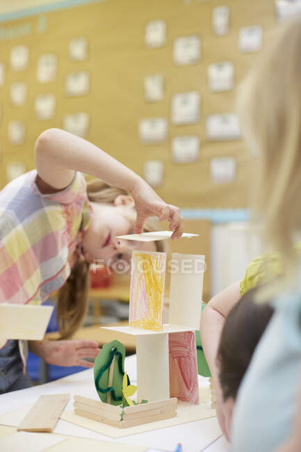 Початкова школярка робить картонну конструкцію на столах класу — стокове фото