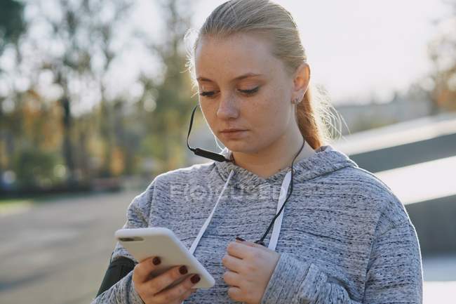 Jovem mulher treinando e olhando para o smartphone — Fotografia de Stock
