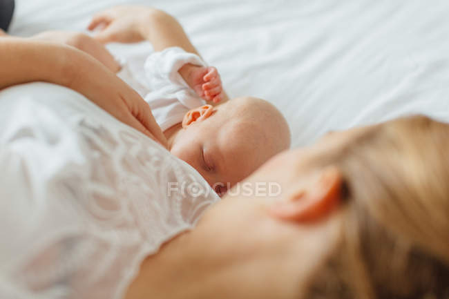 Jovem deitada na cama com a filha bebê — Fotografia de Stock