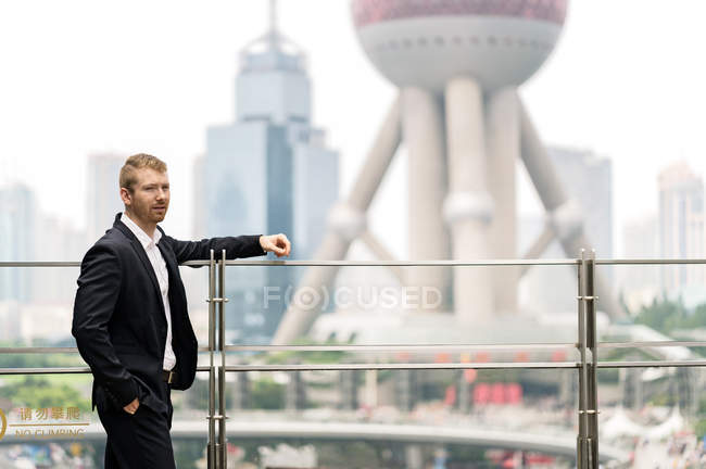 Молодой бизнесмен, опирающийся на перила в финансовом центре Шанхая, Китай — стоковое фото