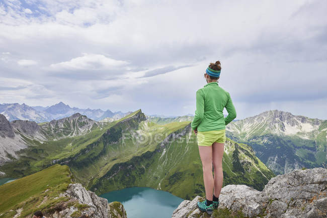 Veduta posteriore dell'escursionista donna sul bordo roccioso guardando sulle montagne di Tannheim, Tirolo, Austria — Foto stock