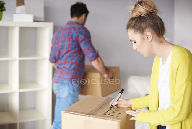 Young woman labeling cardboard box — Stock Photo