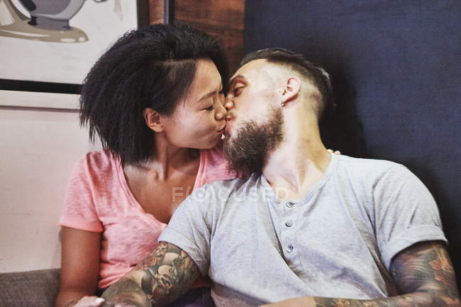 Multi ethnic hipster couple in cafe kissing, Shanghai French Concession, Shanghai, China — Stock Photo