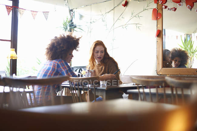 Друзі розслабляються в кафе і дивляться на смартфон — стокове фото