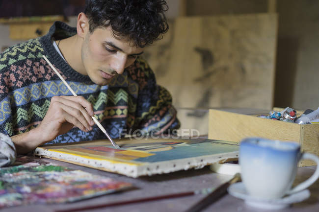 Мужская живопись на холсте в мастерской художника — стоковое фото