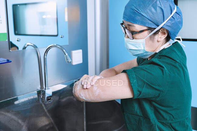 Медсестра театра моет руки в родильном отделении операционной — стоковое фото