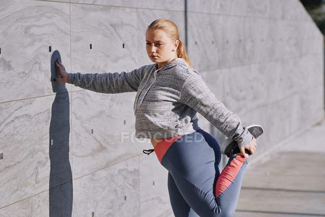 Curvaceous young woman training and stretching leg — Stock Photo