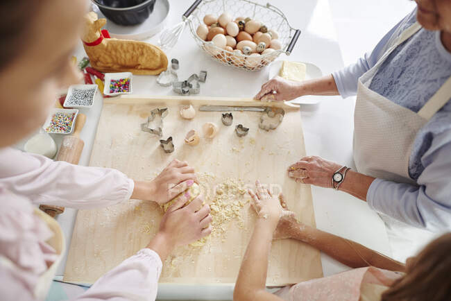 Обрізаний знімок дівчини, матері і бабусі великодньої випічки на кухонній стійці — стокове фото