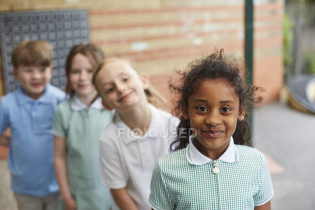 Écolières et garçons debout devant le bâtiment de l'école primaire, portrait — Photo de stock