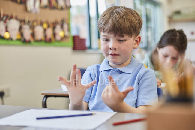 Школярка рахує пальцями на уроці в початковій школі — стокове фото