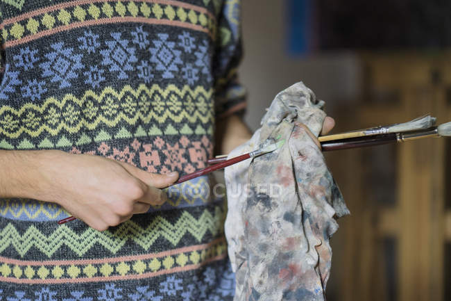 Мужчина чистит кисти в мастерской художника — стоковое фото