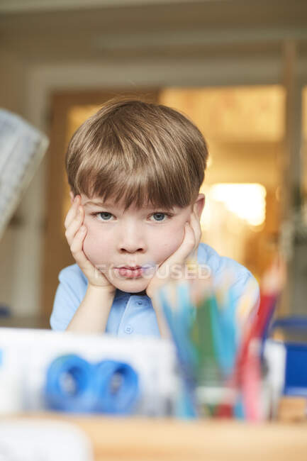 Schoolboy with chin on hands in classroom at primary school, portrait — Stock Photo