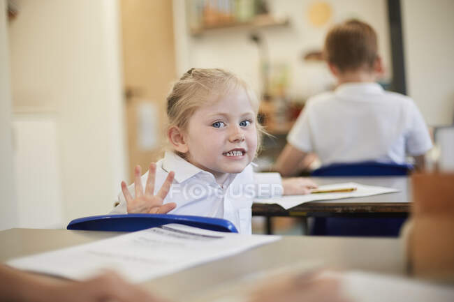 Écolière espiègle en classe à l'école primaire — Photo de stock