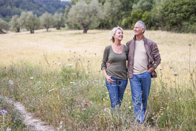 Caminhada de casal braço a braço no campo — Fotografia de Stock
