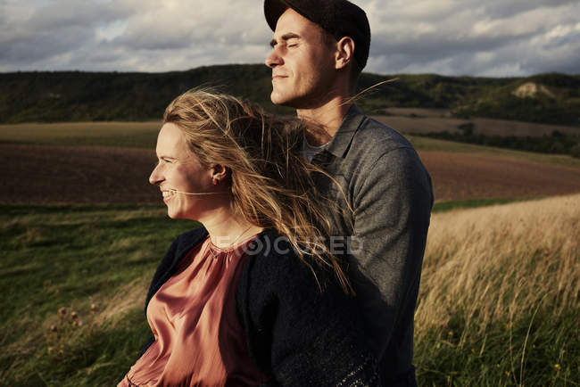 Pregnant adult couple on windy hillside — Stock Photo