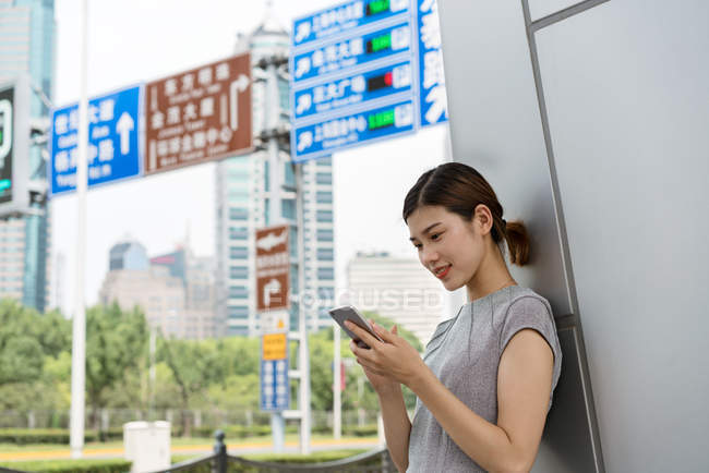 Young businesswoman looking at smartphone in city, Shanghai, China — Stock Photo