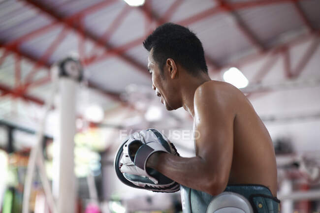 Entrenamiento de boxeador masculino adulto medio en gimnasio - foto de stock