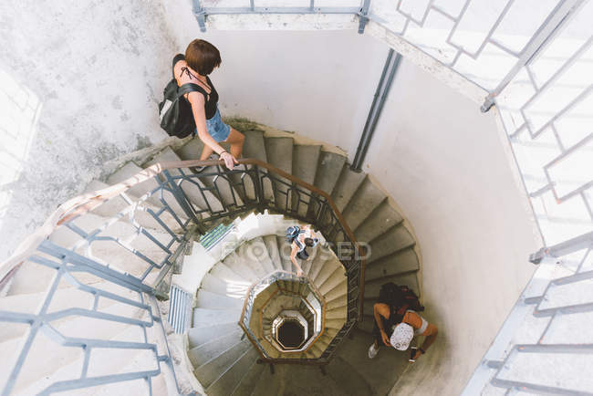 High angle view of three friends moving down on spiral staircase, Como, Lombardy, Italy — Stock Photo