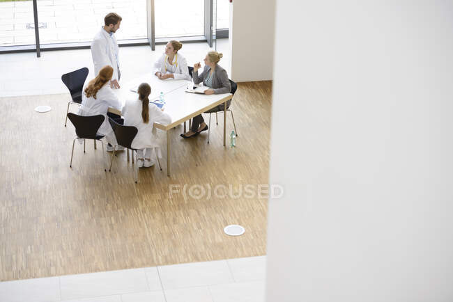 Группа врачей, сидящих за столом, имеющих совещание, повышенный вид — стоковое фото