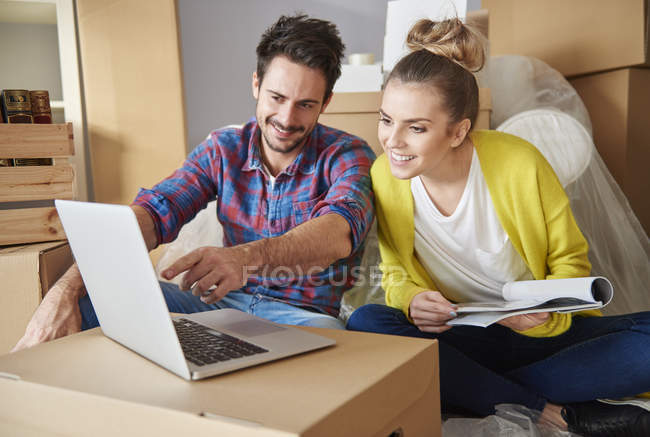 Jeune couple à la nouvelle maison regardant ordinateur portable — Photo de stock