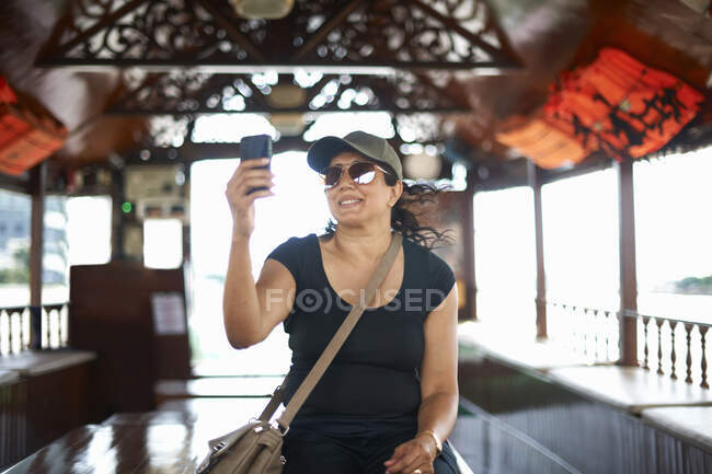 Mujer tomando selfie con teléfono inteligente sonriendo, Bangkok, Krung Thep, Tailandia, Asia - foto de stock