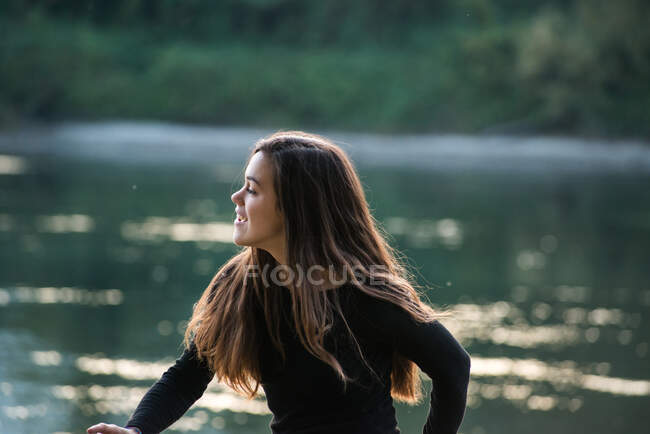 Happy young woman by river, Calolziocorte, Lombardy, Italy — стоковое фото