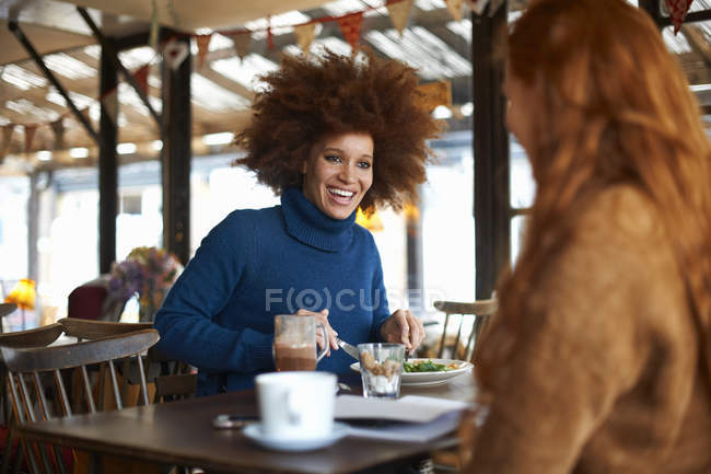Young woman dining in cafe with friend — Stock Photo