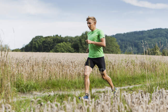 Молодий бігун чоловічої статі біжить уздовж сільської ґрунтової доріжки — стокове фото