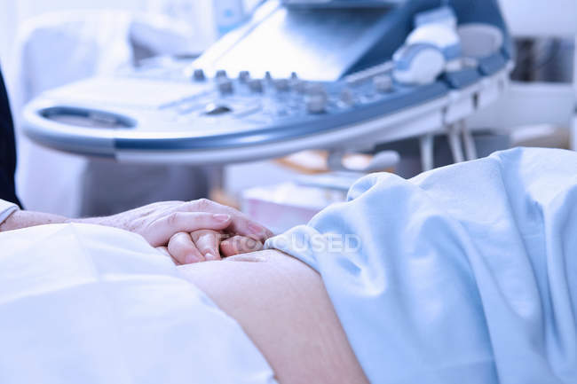 Vue recadrée d'un échographe rassurant une patiente enceinte — Photo de stock
