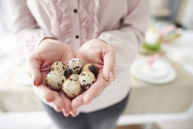 Mid section of woman holding handful of speckled easter eggs — Stock Photo