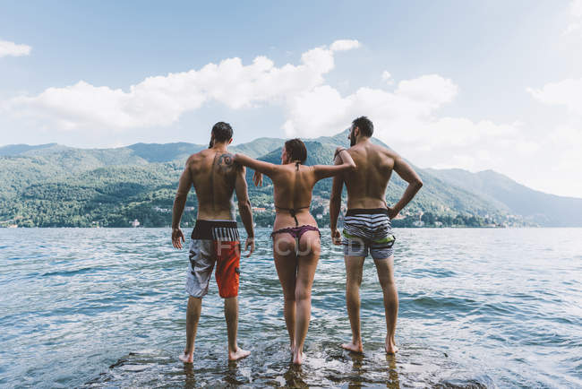 Vista trasera de tres amigos de pie en el lago Como, Como, Lombardía, Italia - foto de stock