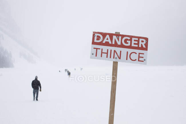 Panneau de danger et personnes sur le lac Louise gelé, Canada — Photo de stock