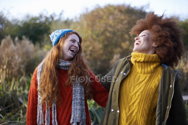Friends arm in arm throwing heads back and laughing — Stock Photo