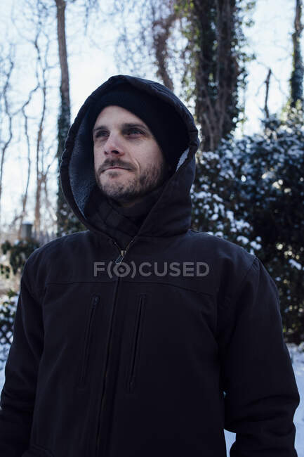 Man keeping warm in hooded jacket in winter weather — Stock Photo