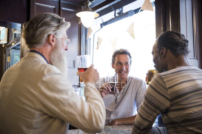 Trois hommes mûrs, assis ensemble dans un pub, parlant — Photo de stock