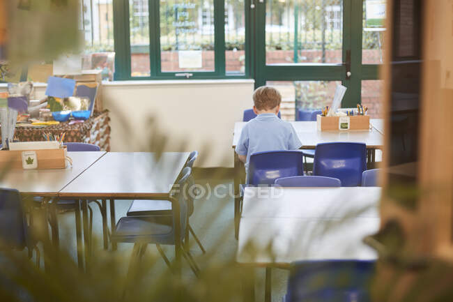 Schuljunge sitzt am Schreibtisch im Klassenzimmer der Grundschule, Rückansicht — Stockfoto
