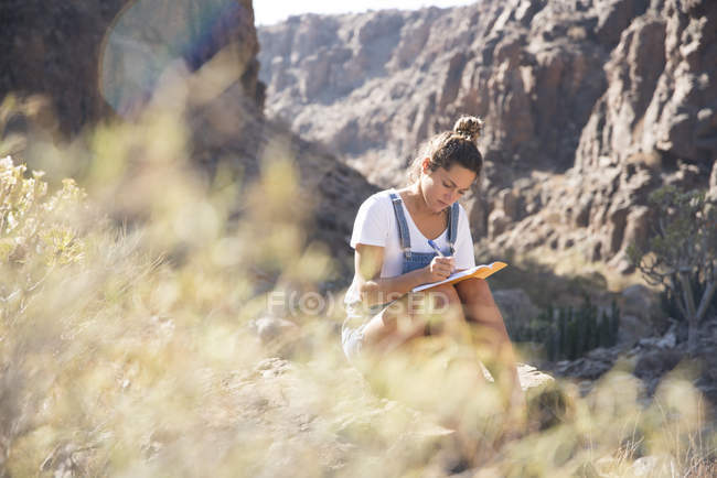 Jovem caminhante escrevendo notas no vale, Las Palmas, Ilhas Canárias, Espanha — Fotografia de Stock