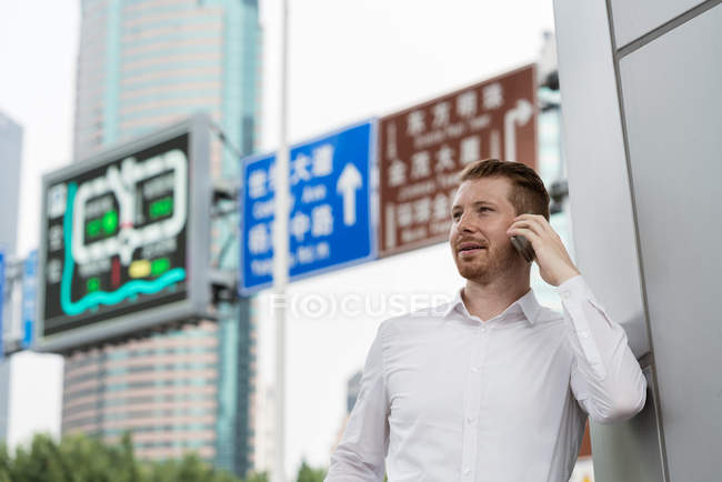Молодой бизнесмен делает смартфон в городе Шанхай, Китай — стоковое фото