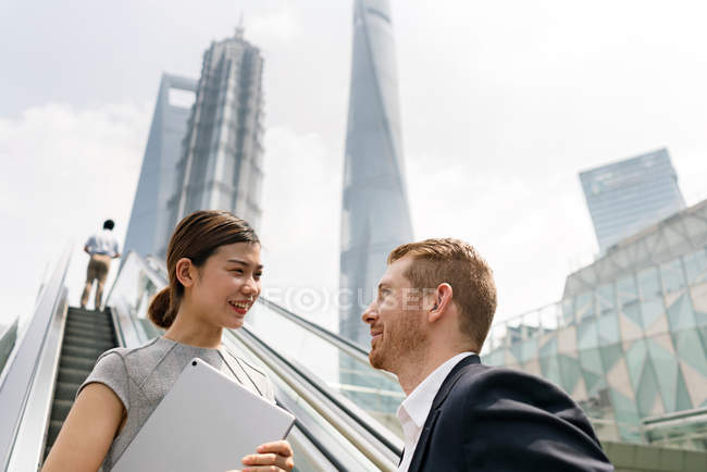 Young business couple on escalator in Shanghai financial centre, China — Stock Photo