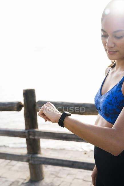 Junge Frau schaut beim Training auf Smartwatch — Stockfoto