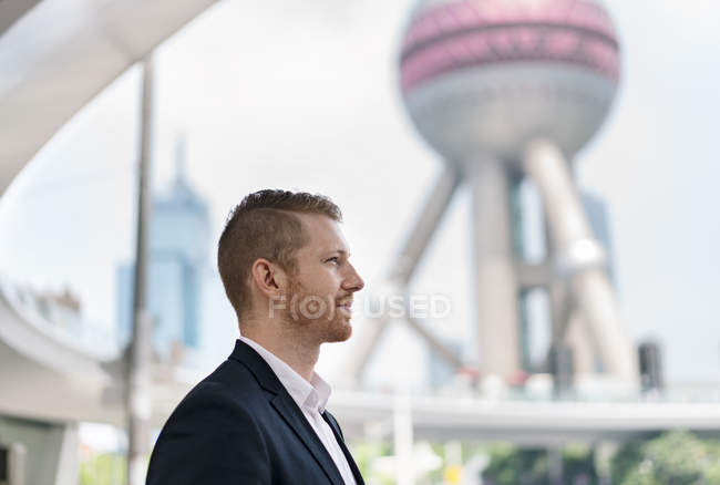 Junger Geschäftsmann blickt weg auf Shanghai Finanzzentrum, China — Stockfoto
