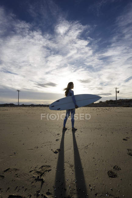 Jovem surfista feminina em pé na praia — Fotografia de Stock