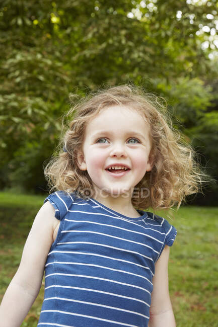 Retrato de chica rubia de pelo ondulado con ojos azules en el parque - foto de stock