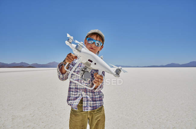 Ritratto di ragazzo su saline, con drone in mano, Salar de Uyuni, Uyuni, Oruro, Bolivia, Sud America — Foto stock