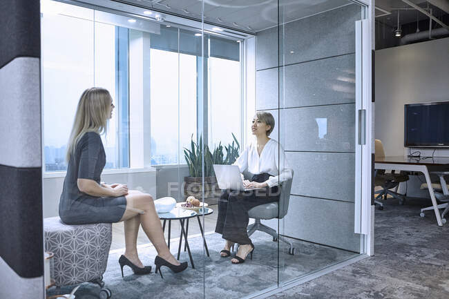 Colleagues having meeting in glass pod in office — Stock Photo