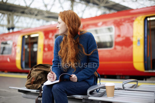 Femme sur banc au quai de la gare — Photo de stock