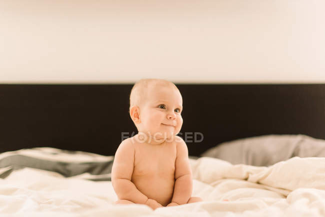 Carina bambina seduta sul letto — Foto stock
