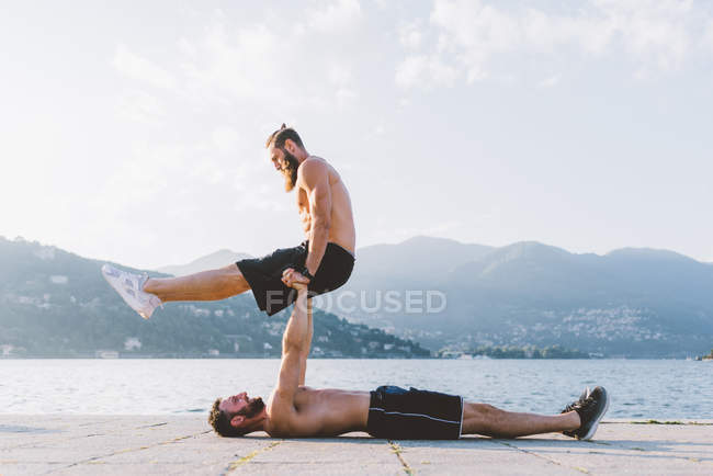 Deux jeunes hommes s'entraînent au bord de l'eau, Lac de Côme, Lombardie, Italie — Photo de stock