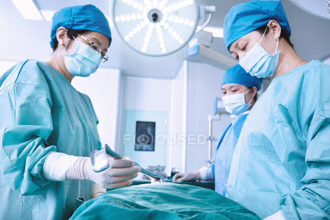 Chirurgiens pratiquant une chirurgie sur l'abdomen de la patiente en salle d'opération de maternité — Photo de stock