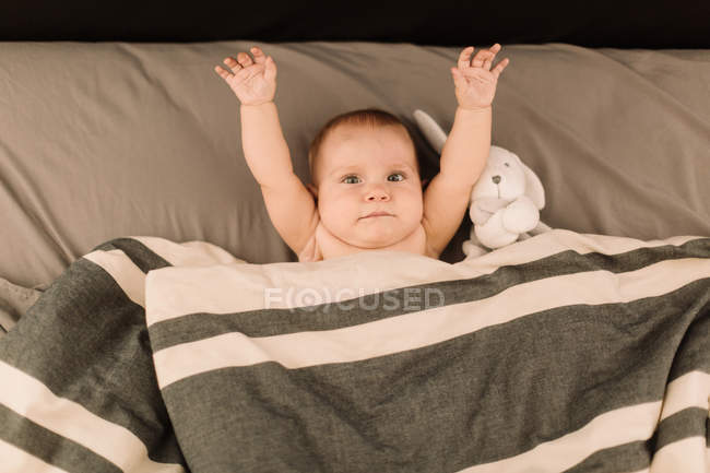 Retrato de bebê menina deitada na cama com brinquedo macio — Fotografia de Stock